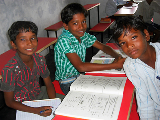 新しい机と椅子で勉強するインドの子どもたち