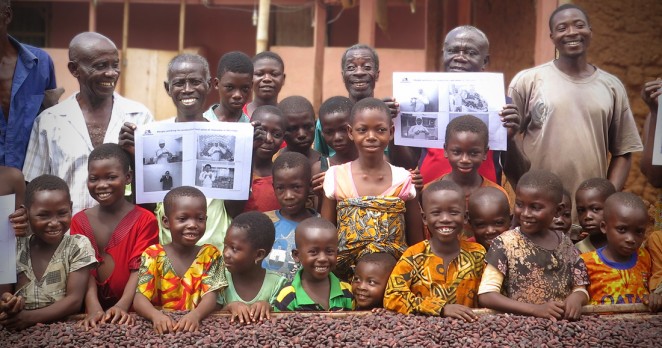 ACEが支援するカカオ生産地の農家と子どもたち（日本から持参した森永製菓社員の写真を持って記念撮影）